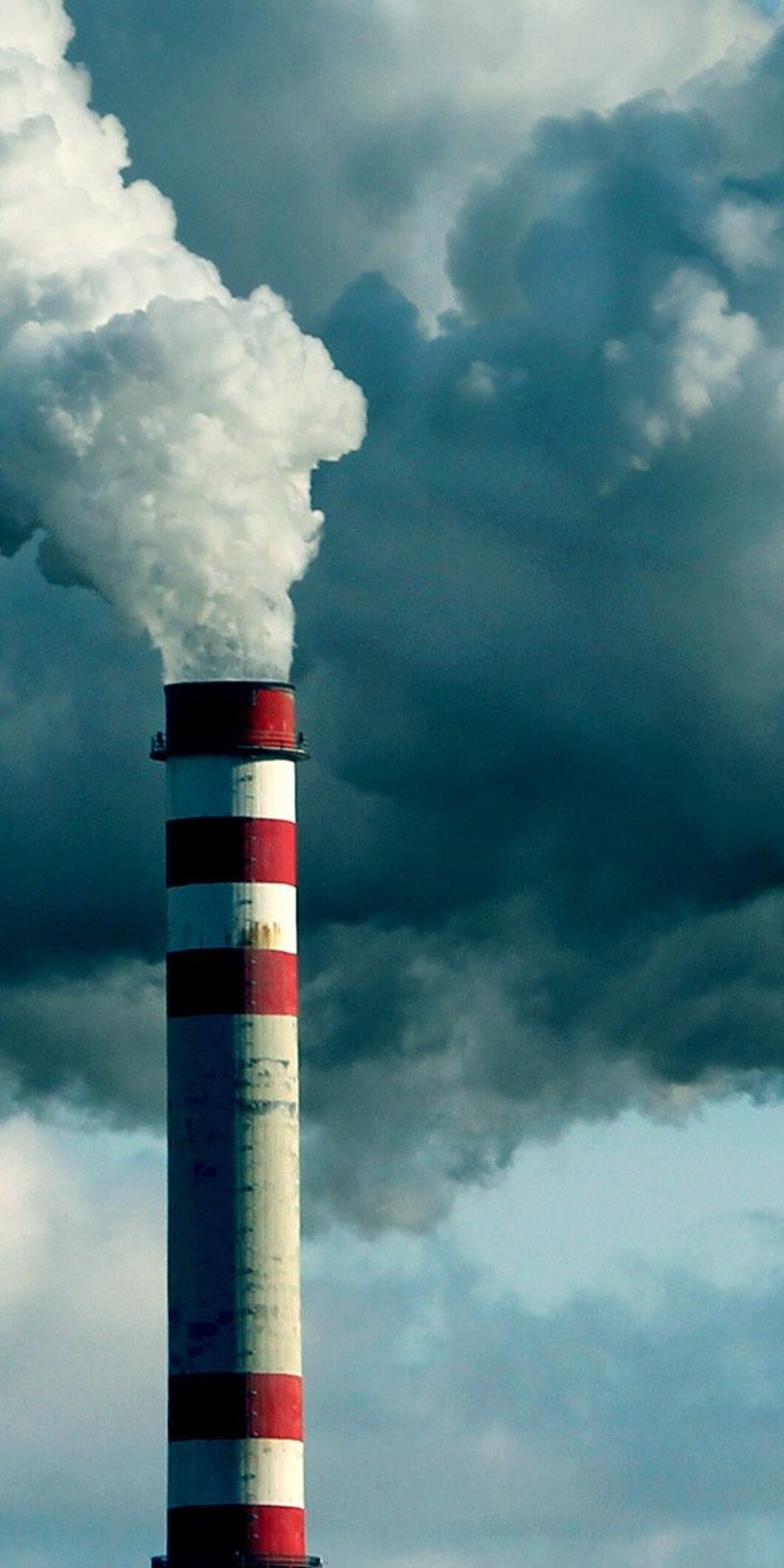 Een fabrieksschoorsteen stoot een grote wolk uit
