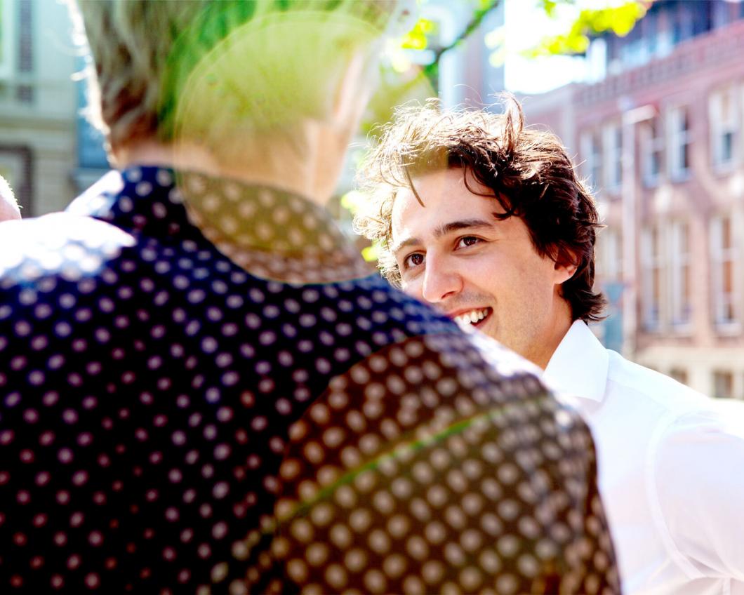 Jesse Klaver lachend naar een persoon waarvan wij alleen de rug zien. 