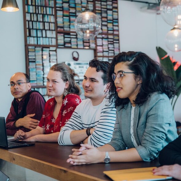 Vier personen zitten naast elkaar en luisteren aandachtig 