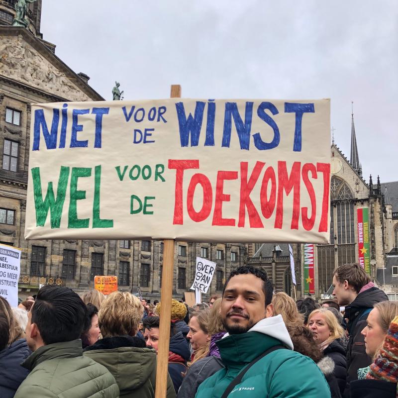 Een demonstrant op een onderwijsprotest houdt een bord vast waarop 'Niet voor de winst, wel voor de toekomst' staat.